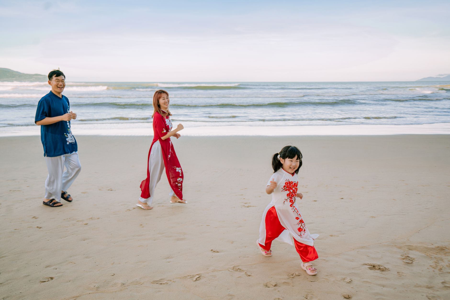 Practical context — Asian family laughing and playing on a sandy beach during the day. (photo: Trần Long)