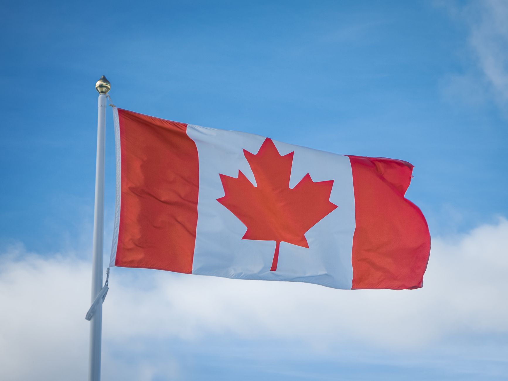 What to Expect on the Ground — A vibrant Canadian flag waving in the breeze against a bright blue sky, symboliz (photo: Jared VanderMeer)