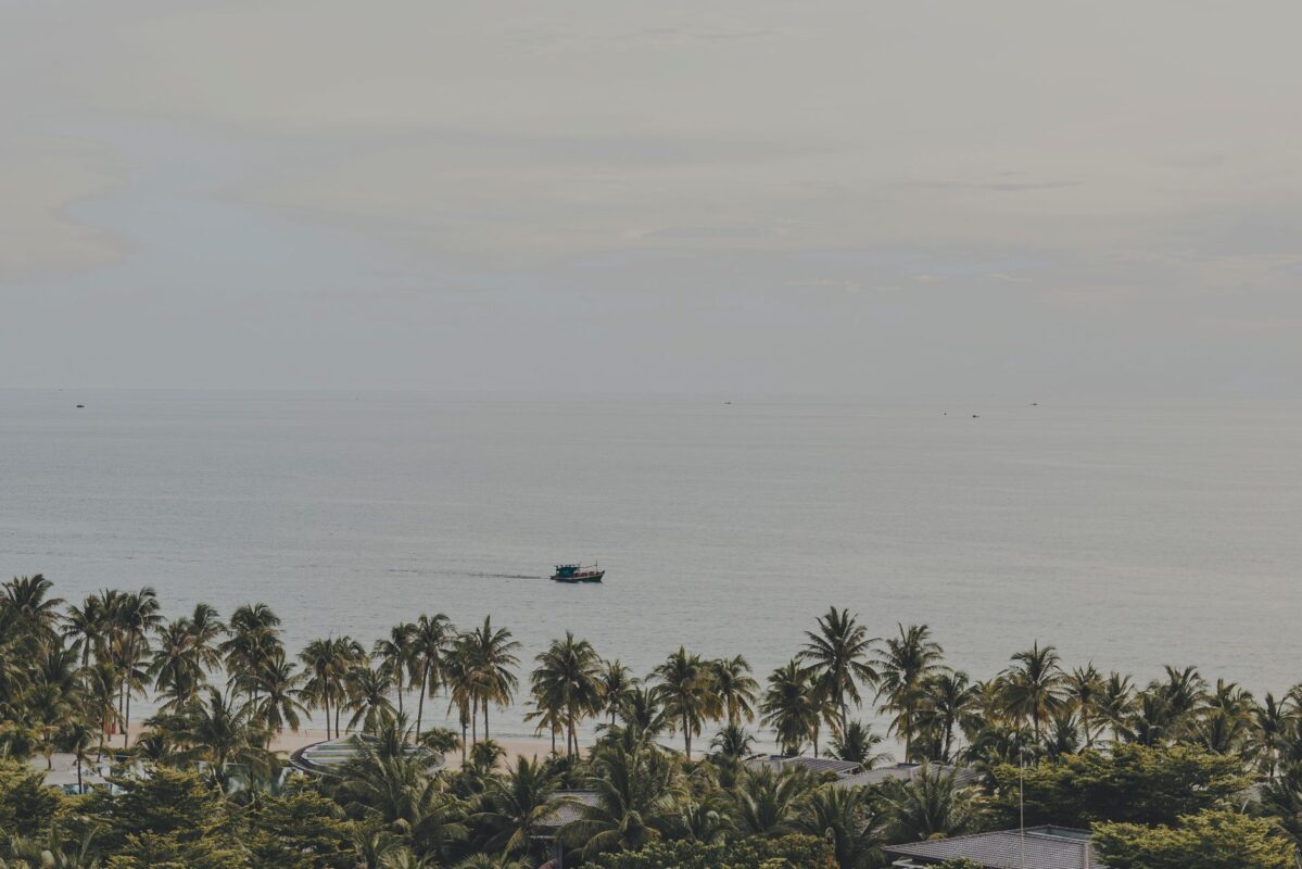 Serene panorama of palm-lined Phu Quoc beach with a distant boat on the calm sea. — photo: Van Trang Ho