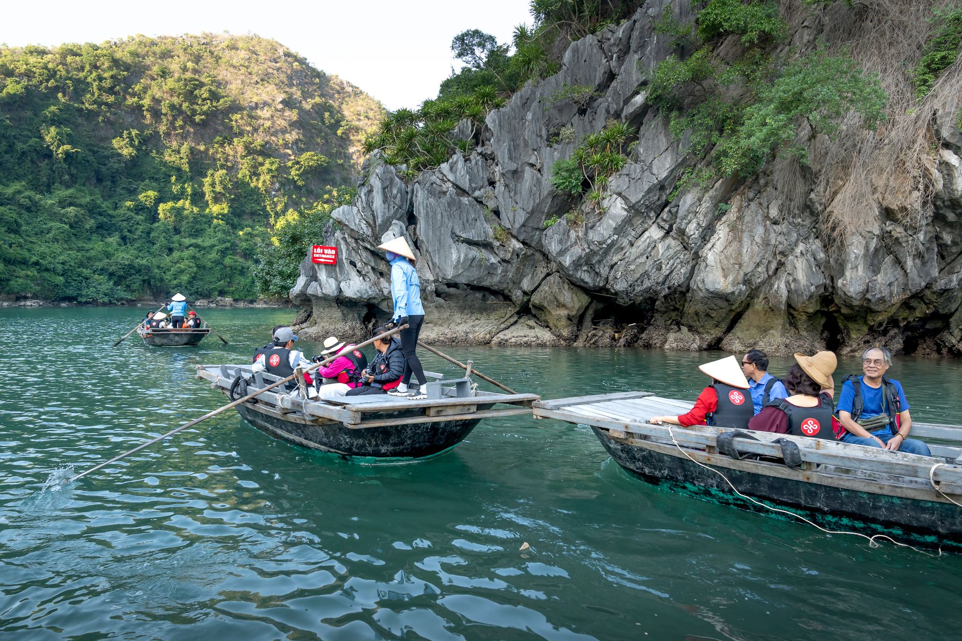 Tourist Singapore Walks in Practice — Tourists in traditional boats explore scenic Halong Bay cliffs. (photo: Quang Nguyen Vinh)
