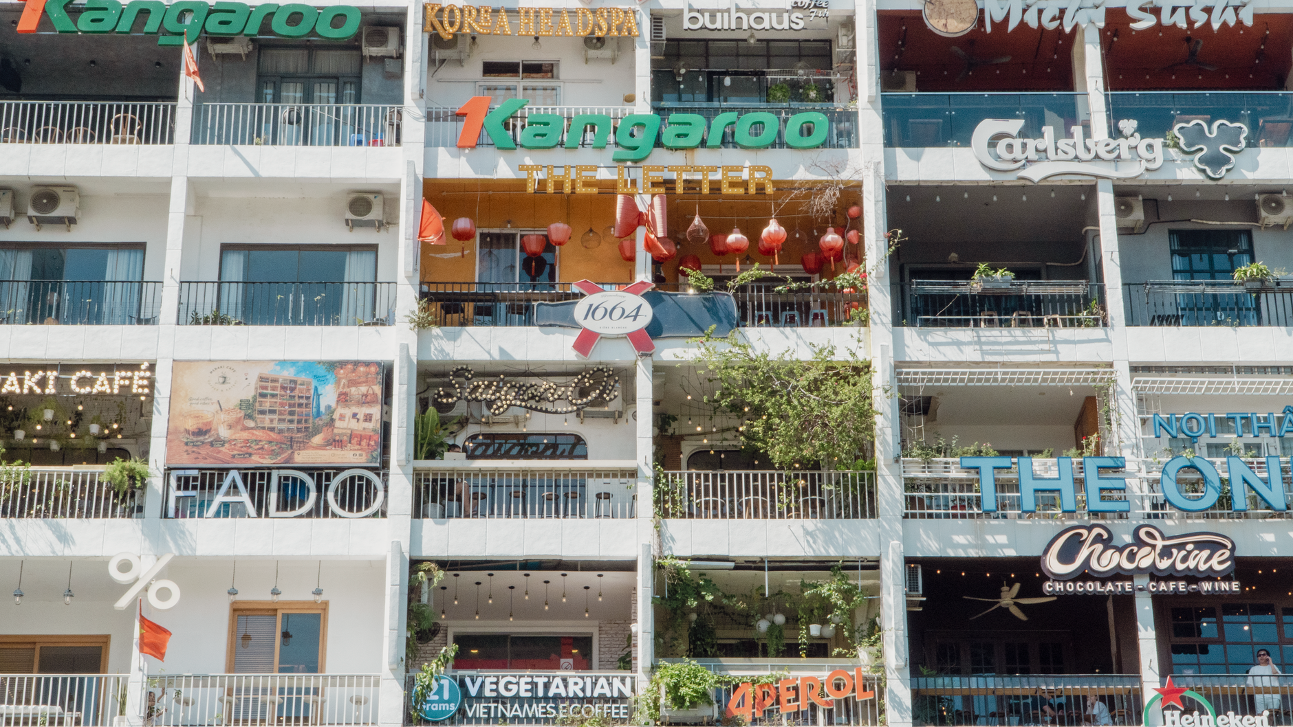 Additional notes — Multi-level building with vibrant cafe signs in Ho Chi Minh City. (photo: Phát Trương)