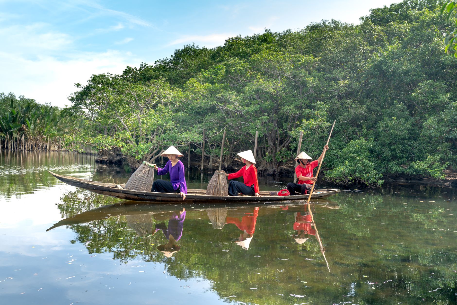 What to Expect on the Ground — Asian fishermen navigate a river in a wooden boat, surrounded by lush mangroves. (photo: Quang Nguyen Vinh)