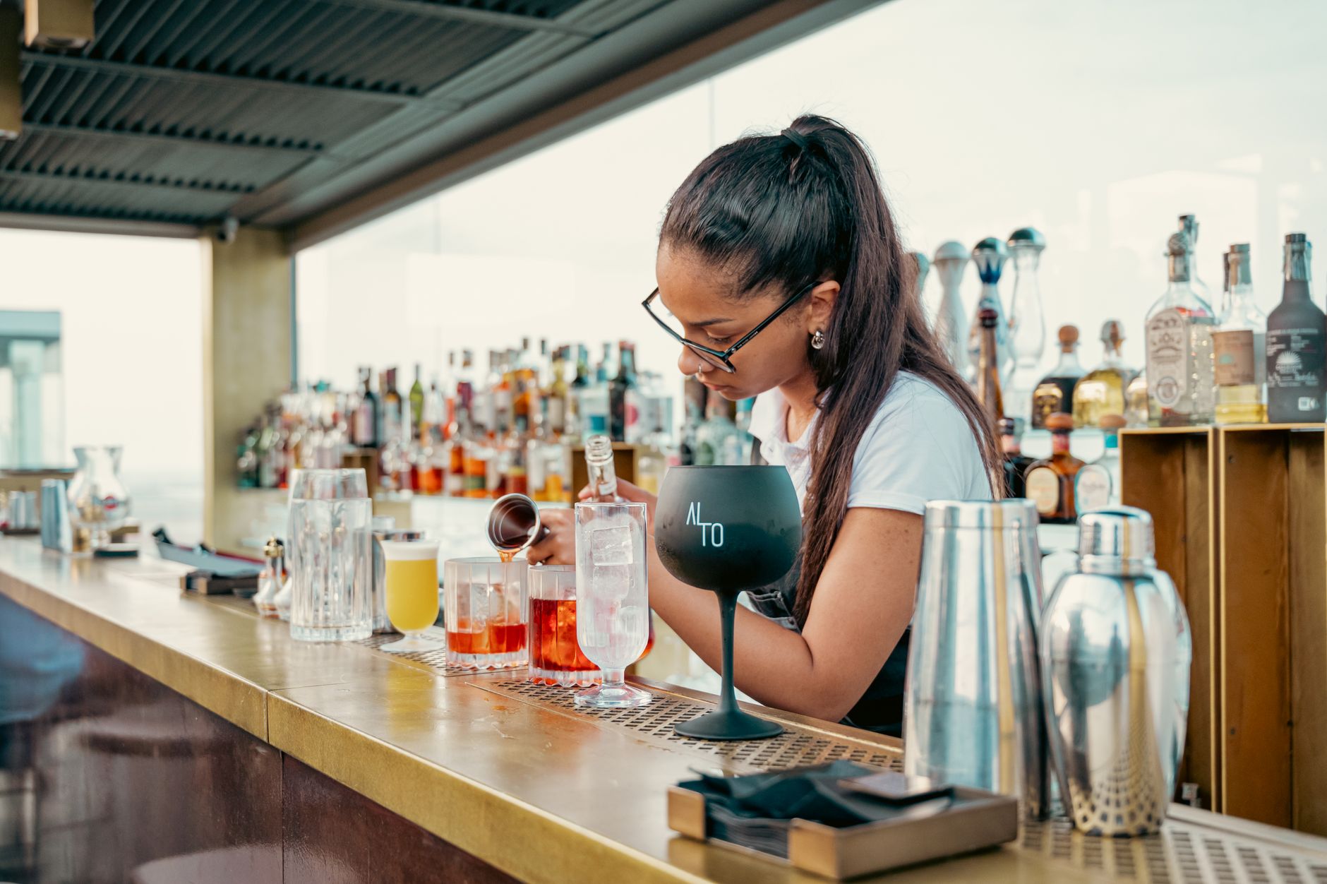 Bartender preparing cocktails at a rooftop bar with city view — photo: Paolo Sbalzer