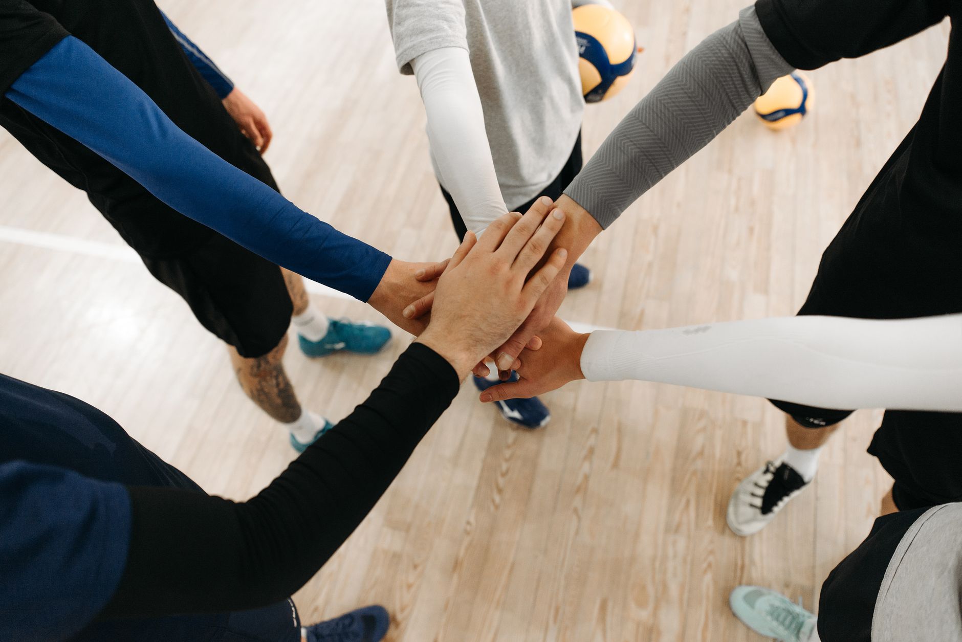 Conclusion — Close-up of athletes joining hands in a motivational sports huddle on an indoor (photo: Pavel Danilyuk)