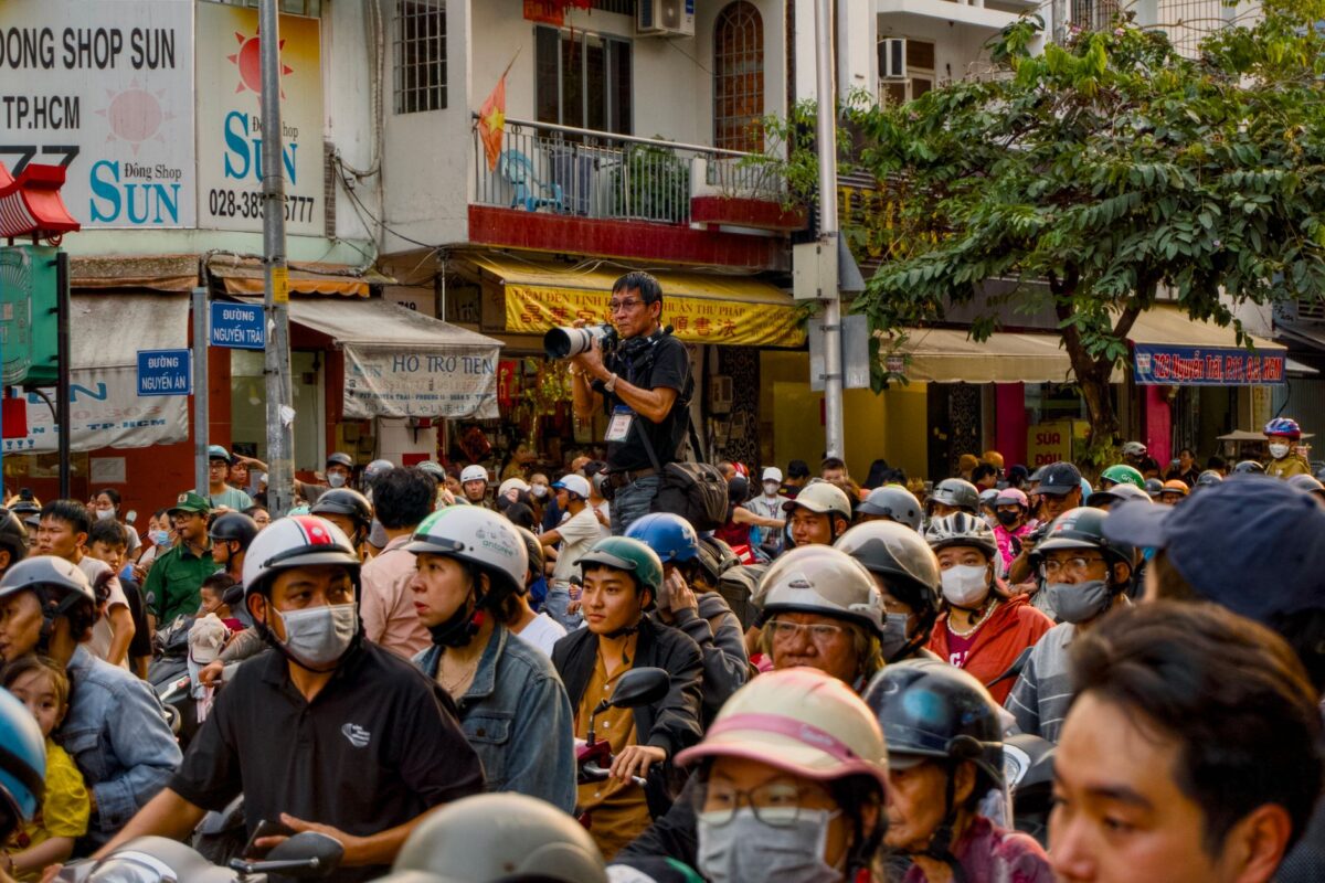 A bustling street packed with people and a photographer taking pictures. β photo: Tuan Vy
