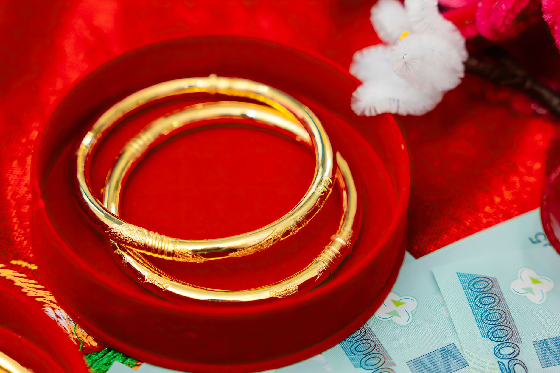 Conclusion — Elegant gold bangles placed on a red fabric with Vietnamese currency. (photo: Phẩm Bùi)