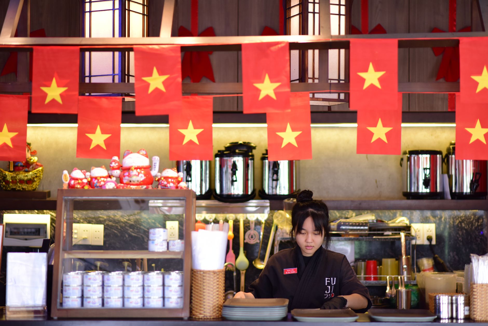 Nearby Ideas — Cozy Vietnamese-themed restaurant interior featuring staff member and cultural d (photo: Sóc Năng Động)
