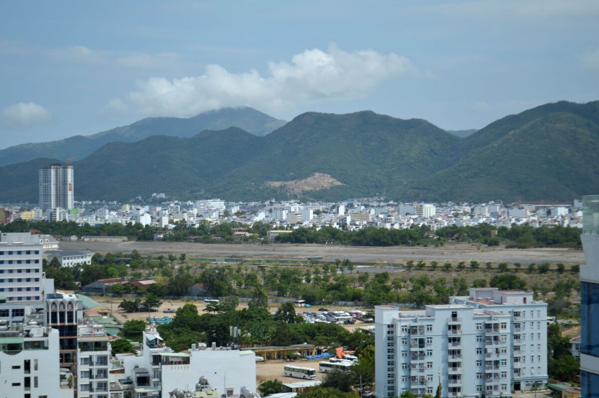 Skyline view of a city framed by lush mountains under a blue sky. — photo: Valeria Drozdova