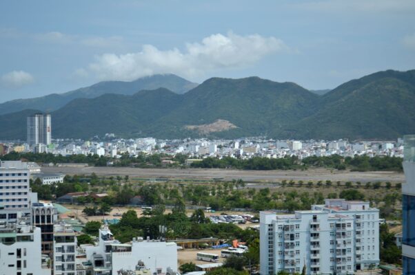 Skyline view of a city framed by lush mountains under a blue sky. — photo: Valeria Drozdova