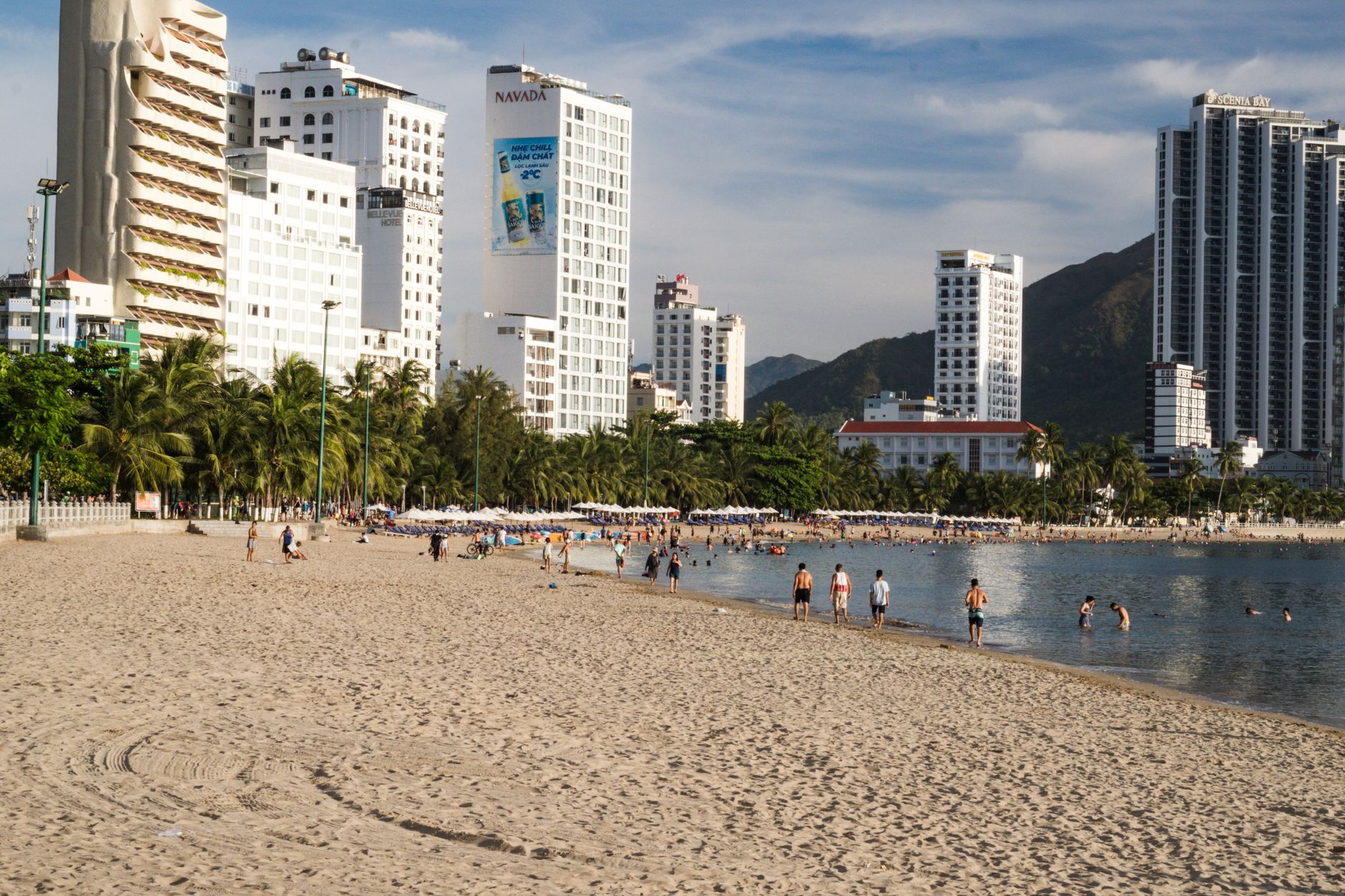 What to Expect on the Ground — Urban beachfront scene with tall hotels, palm trees, and people enjoying a sunny (photo: quang vinh)