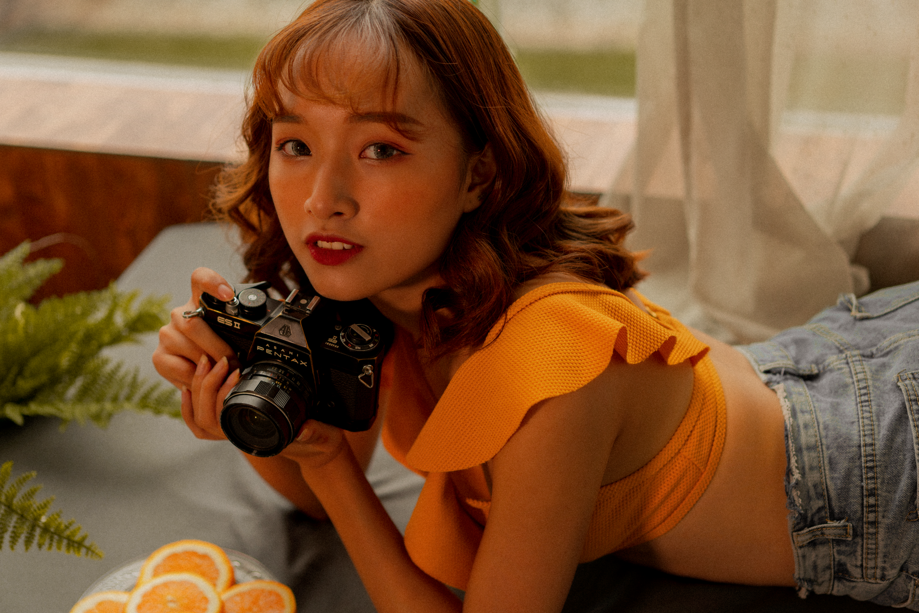What to Expect on the Ground — A young woman poses with a vintage camera in an indoor setting, capturing a styl (photo: Thu Thu)